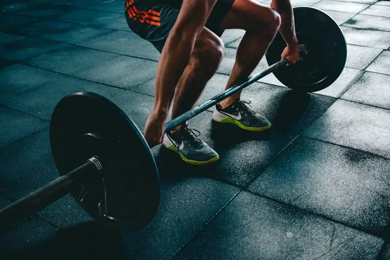 Athlete setting up for a barbell deadlift on a gym floor